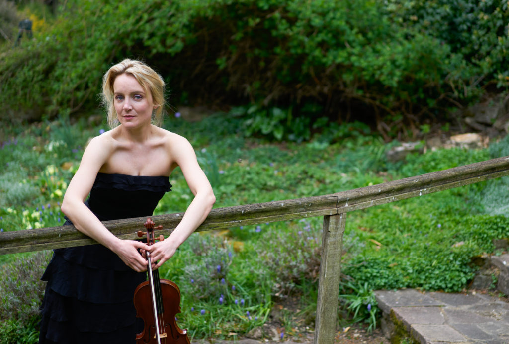 Violinist May Robertson leaning on a fence